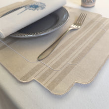 Cargar imagen en el visor de la galería, Mantel individual resinado, tela estilo saco francés, en rayas beige oscuro sobre fondo crudo, y acabado bordado en color crudo. Servilleta de algodón color crudo y bordado flor azul.