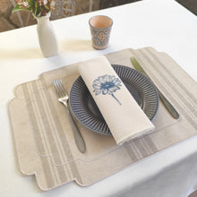 Cargar imagen en el visor de la galería, Conjunto de mantel individual resinado, tela estilo saco francés, en rayas beige oscuro sobre fondo crudo, y acabado bordado en color crudo, y servilleta de algodón crudo, con bordado flores azul, y acabado en festón crudo.