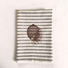 Cargar imagen en el visor de la galería, Servilleta de algodón con rayas azules sobre fondo crudo, con un estilo muy marinero. El bordado es de concha marina realizado con hilo de color marrón
