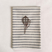 Cargar imagen en el visor de la galería, Servilleta de algodón con rayas azules sobre fondo crudo, con un estilo muy marinero. El bordado es de concha marina realizado con hilo de color marrón.
